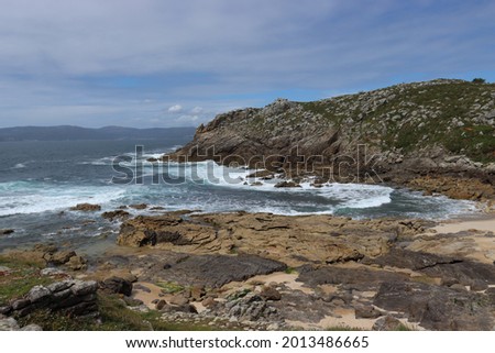 Image of the Galician coast with the rock formations, the choppy sea and the mountains on the other side.