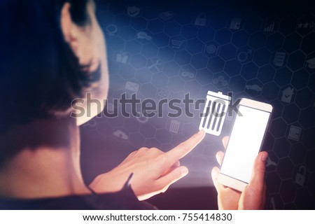 Image of a girl with a smartphone in hands. She presses on the trash can icon. The concept of deleting files, contacts, putting in order, cleaning service etc.