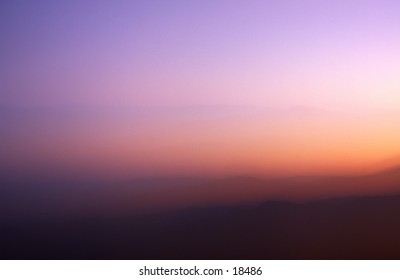 The image is of a glowing mountain sunset displaying a multitude of muted pastel colors.