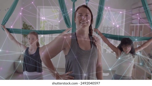 Image of glowing network over diverse female instructor and teenage girls practicing aerial yoga. Wellbeing, energy, fitness, connection and healthy lifestyle, digitally generated image. - Powered by Shutterstock