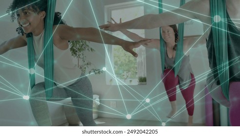 Image of glowing network over diverse female instructor and teenage girls practicing aerial yoga. Wellbeing, energy, fitness, connection and healthy lifestyle, digitally generated image. - Powered by Shutterstock