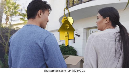 Image of golden key and house over diverse couple carrying cartons at home. Moving house and home concept digitally generated image. - Powered by Shutterstock