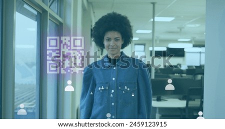 Image of gr code and icons over biracial woman smiling in office. Business, working in office and technology concept digitally generated image.