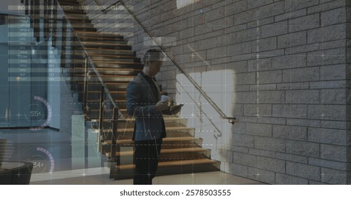 Image of graphs and charts over caucasian businessman using smartphone at office foyer. Business, connection, data, processing, digital interface and communication, digitally generated image.