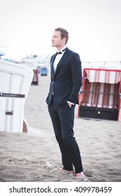 an image of groom posing on the beach