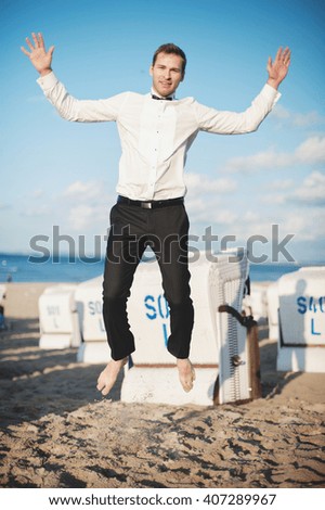 an image of groom posing on the beach