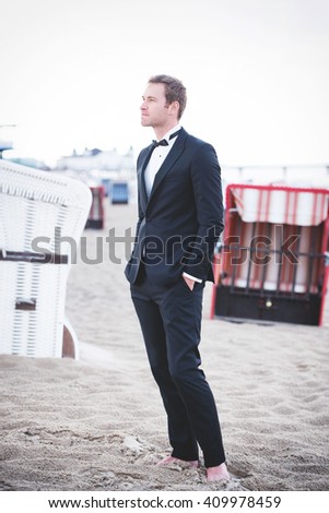 an image of groom posing on the beach