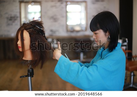Image of a hairdresser practicing cutting hair 