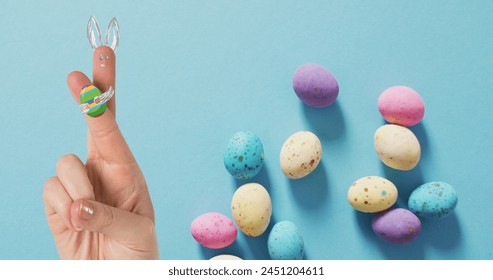 Image of hand with easter decorations and easter eggs over blue background. easter, tradition and celebration concept digitally generated image. - Powered by Shutterstock - Get 15% off with code: PIKWIZARD15