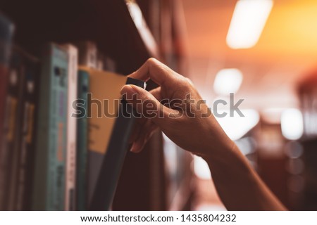 
Image of a hand selecting a book from a bookshelf