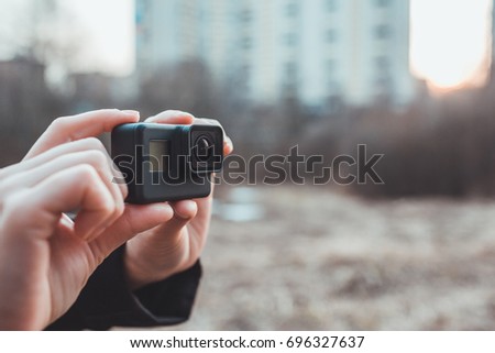 an image of hands holding small action camera 
