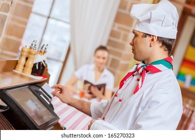 Image of handsome chef inserting card in terminal