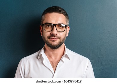 Image of handsome man standing over dark blue background looking camera.