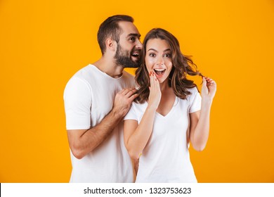 Image of handsome man whispering secret or interesting gossip to woman in her ear isolated over yellow background - Powered by Shutterstock