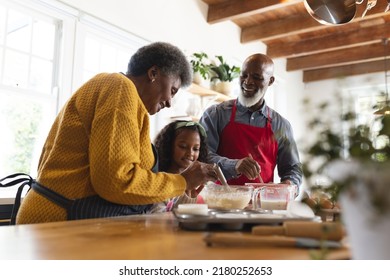 Image of happy african american grandparents and granddaughter baking in kitchen. Family and spending quality time together concept. - Powered by Shutterstock