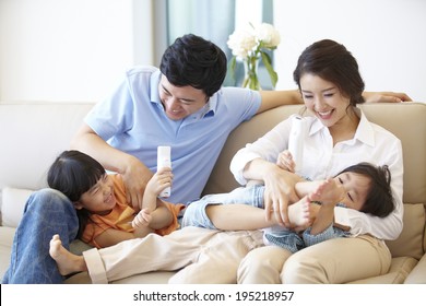 The Image Of A Happy Asian Family Laughing On Couch