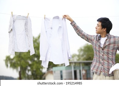 The Image Of A Happy Asian Father Hanging Out Clothes