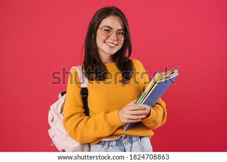 Image of happy beautiful student girl posing with exercise books isolated over pink background