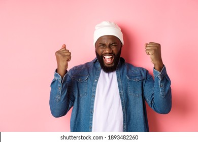 Image Of Happy Black Man Winning In Lottery, Rejoicing And Making Fist Pump, Scream Yes In Joy, Standing Over Pink Background