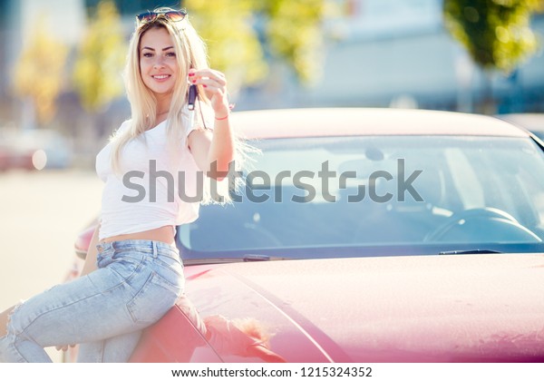 Image of happy blonde woman with keys standing near\
red car on summer day.