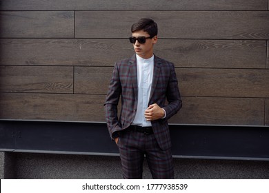 Image Of Happy Brunette Man Wearing Formal Clothes, Serious Facial Expression Looking Not At Camera With Hands In Pockets On Brown Plates Background.