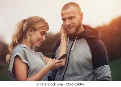 Image of happy fitness sport loving couple friends in park outdoors listening music with earphones. - Powered by Shutterstock