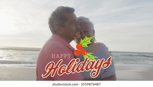 Image of happy holidays text over happy senior biracial couple embracing on beach at christmas. Christmas, holidays, festivity, tradition and celebration concept digitally generated image. - Powered by Shutterstock