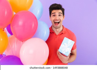 Image Of Happy Joyful Man Celebrating Birthday With Multicolored Air Balloons And Gift Box Isolated Over Violet Background