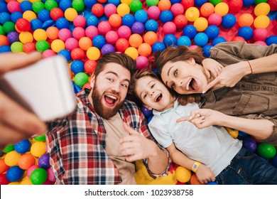 Image of happy little child have fun with his parents in entertainment game center. Looking aside make selfie by phone pointing. - Powered by Shutterstock