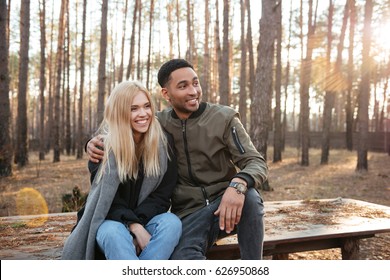 Image of happy loving couple sitting outdoors in the forest. Looking aside. స్టాక్ ఫోటో