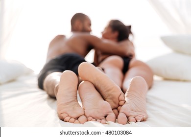 Image of happy multiracial couple laying at the white beach bed and embracing