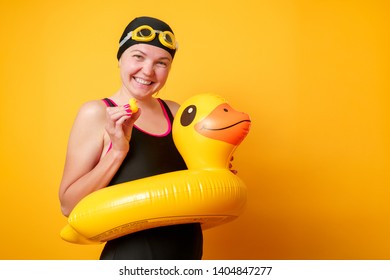 Image of happy woman in bathing suit with lifebuoy on empty orange background - Shutterstock ID 1404847277