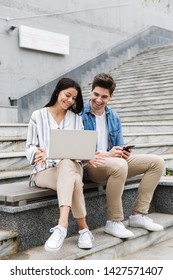 Image Of Happy Young Amazing Loving Couple Business People Colleagues Outdoors Outside On Steps Using Mobile Phone And Laptop Computer.