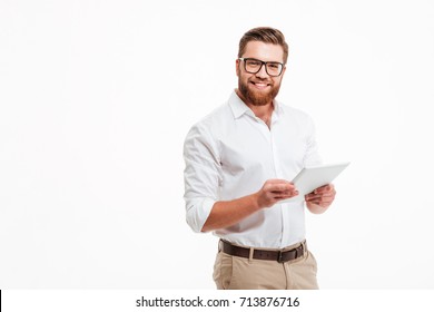 Image of happy young bearded man standing over white wall background isolated. Looking camera using tablet computer. - Powered by Shutterstock