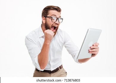 Image Of Happy Young Bearded Man Standing Over White Wall Background Isolated. Looking Aside Using Tablet Computer Make Winner Gesture.