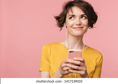 Image of a happy young beautiful woman posing isolated over pink wall background listening music with earphones using mobile phone. - Shutterstock ID 1417139033