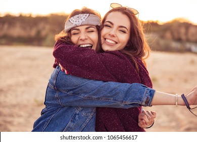 Image of happy young caucasian friends ladies walking outdoors on the beach hugging.