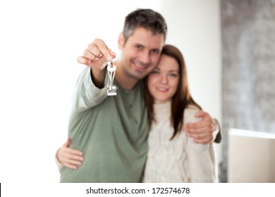 Image Of Happy Young Couple Smiling And Holding Key Ring, Shallow Depth Of Field Focus On Foreground