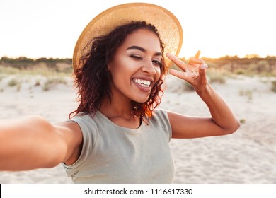 Image Of Happy Young Excited African Lady Make Selfie By Camera With Peace Gesture On The Beach.