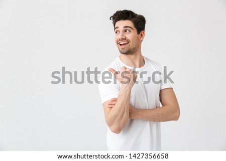 Image of a happy young excited emotional man posing isolated over white wall background. Looking aside pointing.