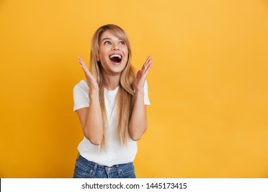 Image of a happy young excited shocked blonde woman posing isolated over yellow wall background looking aside.