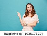 Image of happy young lady standing isolated over blue background. Looking camera pointing.