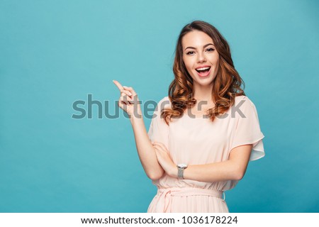 Photo of Image of happy young lady standing isolated over blue background. Looking camera pointing.