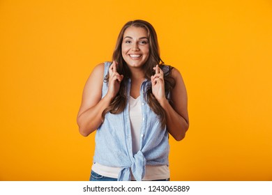 Bild einer glücklichen jungen Frau, die einzeln auf gelbem Hintergrund steht und eine hoffnungsvolle Geste zeigt.