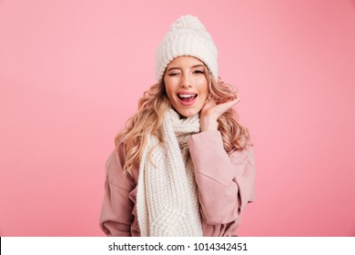 Image of happy young woman standing isolated over pink background wearing warm scarf. Looking camera.