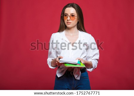 Image of happy young woman student isolated over pink wall background. Looking camera writing notes.