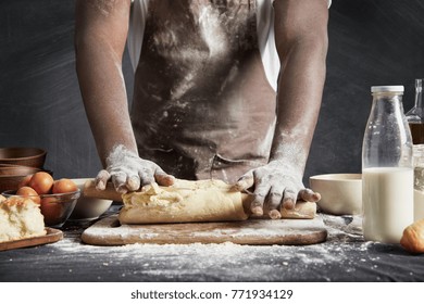 Image Of Hard Working Male Cook Or Baker With Dark Skin Wears Apron, Sheets Well Made Dough, Going To Bake Tart, Isolated Over Black Chalk Background. Unrecognizable African American Chef On Kitchen