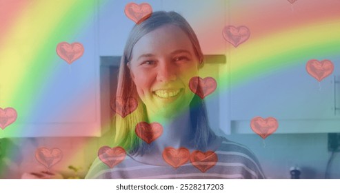 Image of heart emojis and rainbow flag over caucasian woman smiling. Lgbtq, love, romance and celebration concept digitally generated image. - Powered by Shutterstock