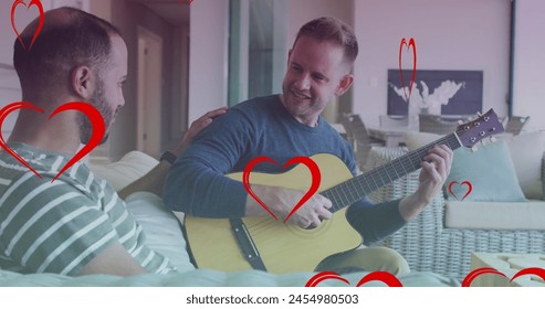 Image of heart icons over diverse gay couple smiling and playing guitar. pride month and celebration concept digitally generated image. - Powered by Shutterstock