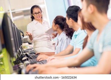 Image Of A High School Teacher Teaching In The Computer Classroom On The Foreground